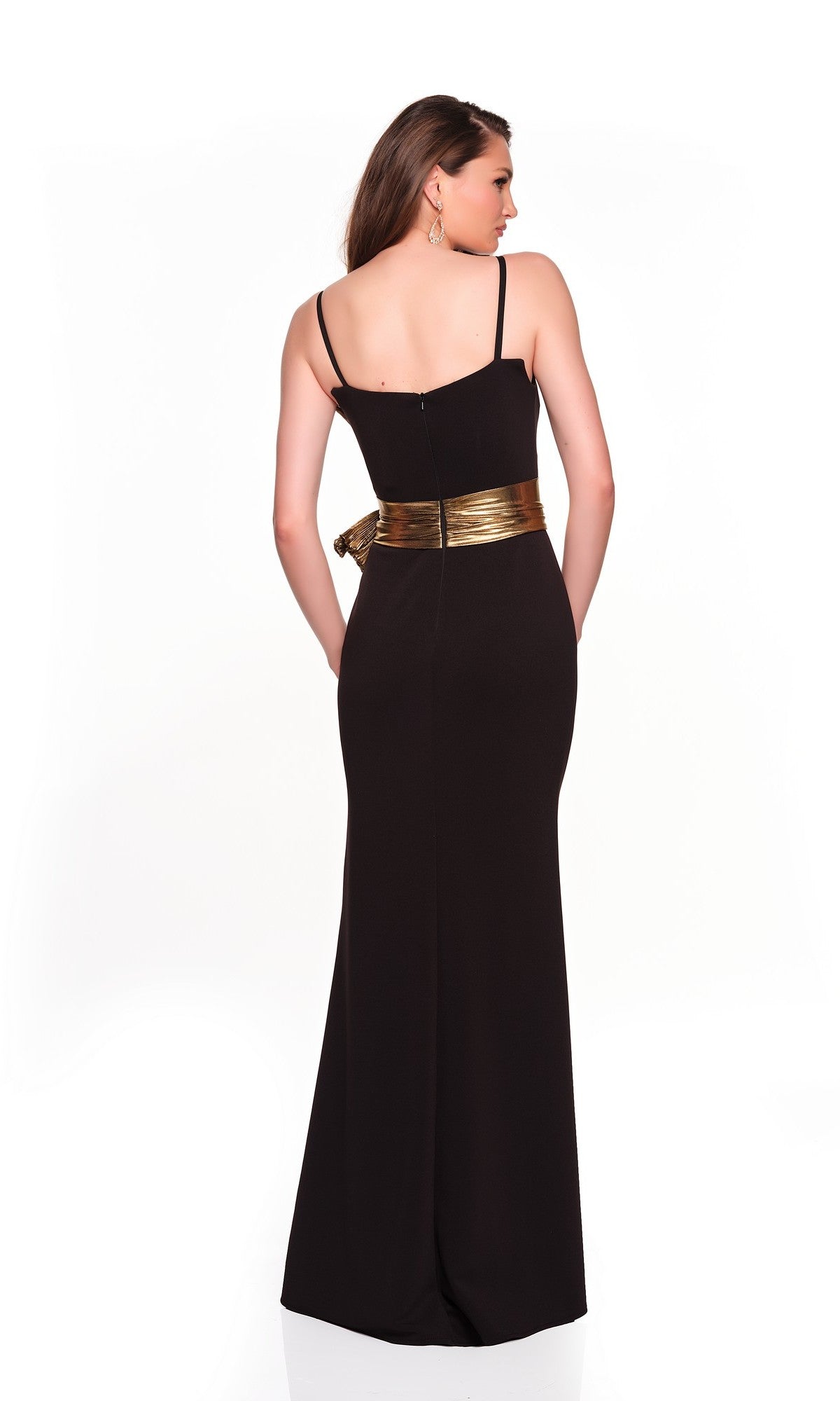 A woman stands with her back to the camera, wearing the Dave and Johnny 12666 long black prom dress with thin straps, a shiny gold belt, and a sleek sheath skirt, set against a plain white background.